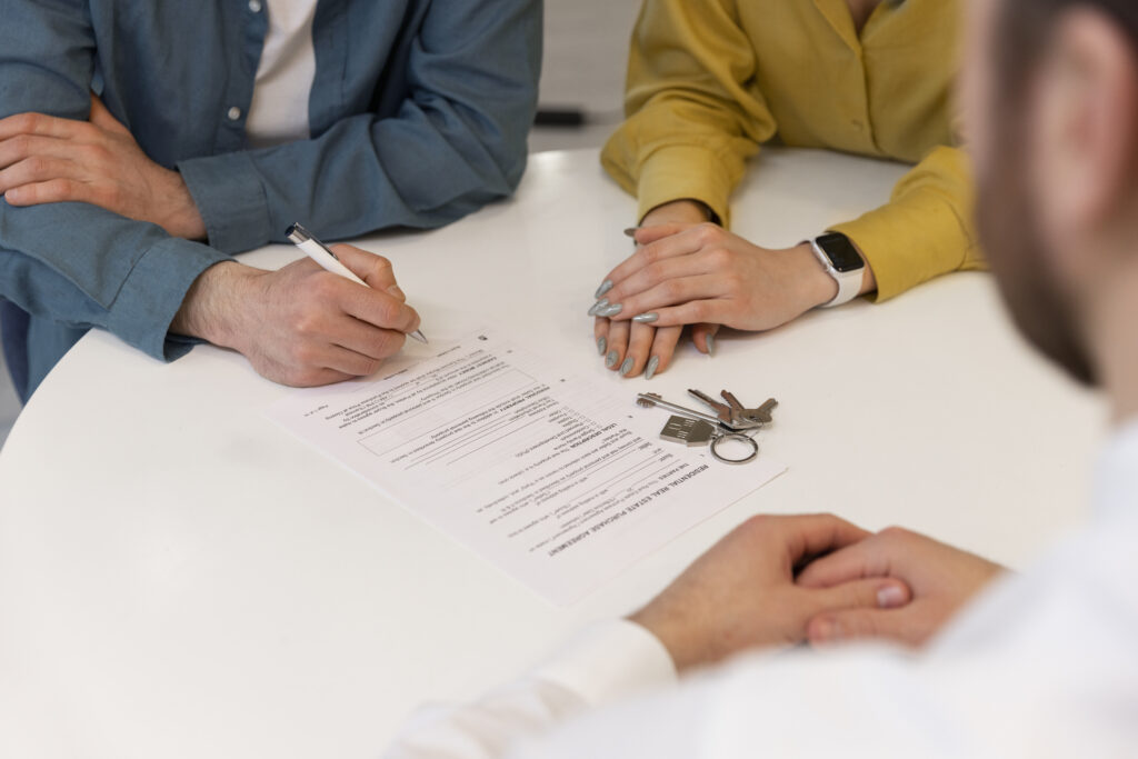 trois personnes autour d'une table avec des documents d'acquisition d'un bien immobilier