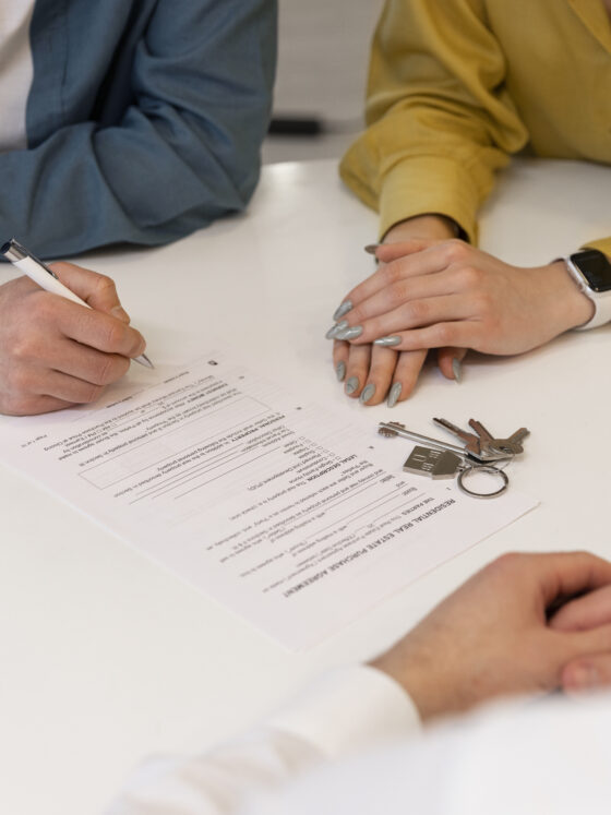 trois personnes autour d'une table avec des documents d'acquisition d'un bien immobilier